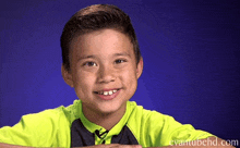 a young boy in a neon green shirt is smiling in front of a blue background with evantubehd.com written on the bottom