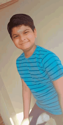 a young boy wearing a blue striped shirt is smiling for the camera