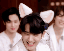 a boy wearing a cat ear headband is smiling in front of two other men .