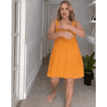 a woman in a yellow dress is dancing in a hallway .