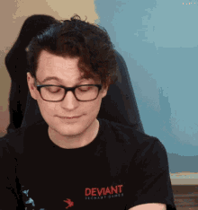 a man wearing glasses is wearing a deviant dechart games shirt