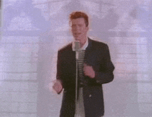 a man in a suit is standing in front of a microphone and singing into it .