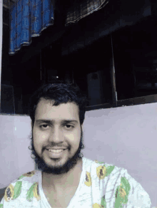 a man with a beard is smiling and wearing a white shirt with a sunflower on it