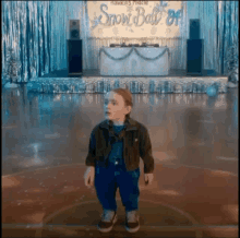 a little boy standing in front of a snow ball sign