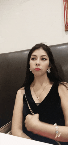 a woman wearing a necklace and earrings is sitting at a table