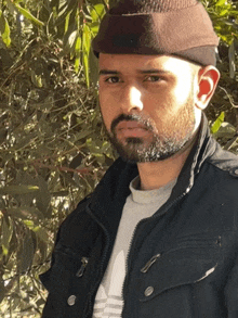 a man with a beard wearing a black jacket and a beanie