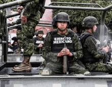 a group of soldiers are sitting in the back of a pickup truck .