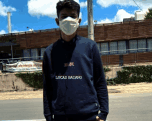 a young man wearing a mask and lucas batano sweatshirt