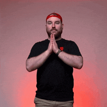 a man wearing a red hat and a black shirt is praying with his hands folded