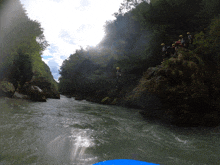 a group of people in yellow helmets stand on a rock overlooking a river