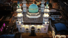 an aerial view of a mosque with a green dome at night