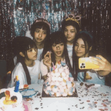 a group of girls are taking a selfie with a birthday cake