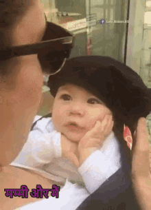 a baby wearing a black hat is being held by a woman with the words cute babies written on the bottom