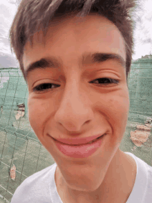 a close up of a young man 's face with a fence in the background