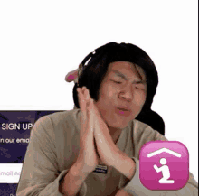 a man wearing headphones is making a funny face with his hands folded in front of a sign up button .