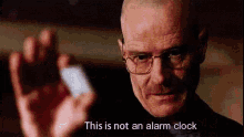 a bald man wearing glasses is holding a piece of paper in his hand and says `` this is not an alarm clock '' .