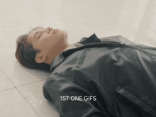 a man in a leather jacket is laying on the floor