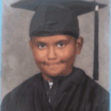 a young boy in a graduation cap and gown smiles for the camera