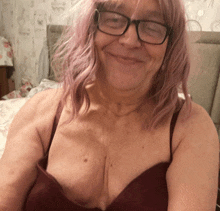 a woman with pink hair wearing glasses and a bra