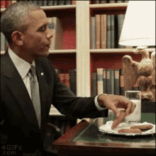 a man in a suit and tie is sitting at a desk with a plate of cookies and a glass of milk