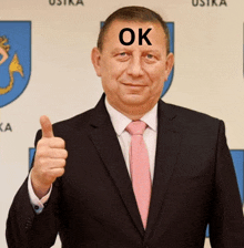 a man in a suit and tie with the word ok on his forehead