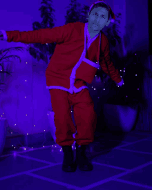 a man in a santa suit is dancing in front of a blue background