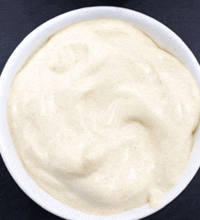 a close up of a bowl of white sauce on a table .