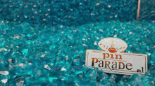 a sign that says pin parade is sitting on top of a pile of blue glass beads .