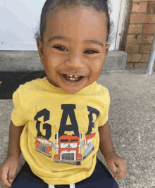 a little boy wearing a yellow gap shirt with trucks on it