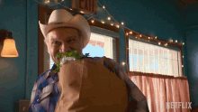 a man in a cowboy hat is holding a bag of food in front of a sign that says exit