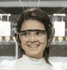 a woman wearing headphones and safety goggles smiles