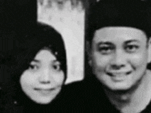 a black and white photo of a man and a woman smiling for the camera .