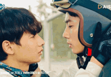 a man wearing a helmet with the word ais on it looks at another man