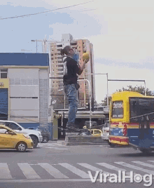 a man is standing on a pole holding a ball in front of a bus that says " festival " on it