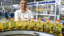 a man is standing in front of a conveyor belt filled with bottles of liquid .