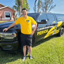 a man in a yellow shirt is standing in front of a truck that says cleans everything period