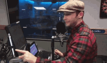 a man in a plaid shirt is sitting in front of a microphone in front of a sign that says radio