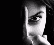 a close up of a woman 's face with a finger pointing at her eye .