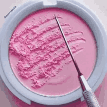 a close up of a pink blush powder with a needle in it .