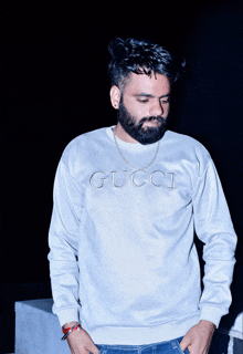 a man with a beard wears a white gucci sweater