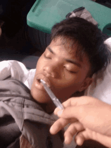 a person is holding a syringe in front of a boy 's mouth