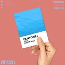 a person is holding a blue pantone color card