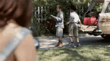 a woman is taking a picture of two boys standing in front of a car with the trunk open .