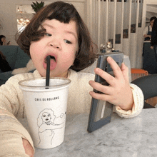 a little girl drinking from a cup that says cafe de rollang