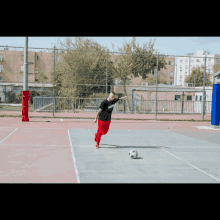 a man kicks a soccer ball on a basketball court