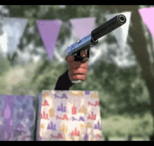 a person is holding a gun over a gift bag with a bottle of wine on it