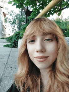 a woman with long red hair and bangs looks at the camera