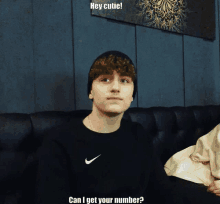 a young man wearing a black nike shirt is sitting on a couch