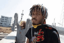 a man with dreadlocks is standing next to a woman in a striped shirt on a bridge .