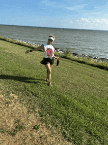 a woman wearing a visor and a t-shirt that says ' the rolling stones ' is standing in the grass